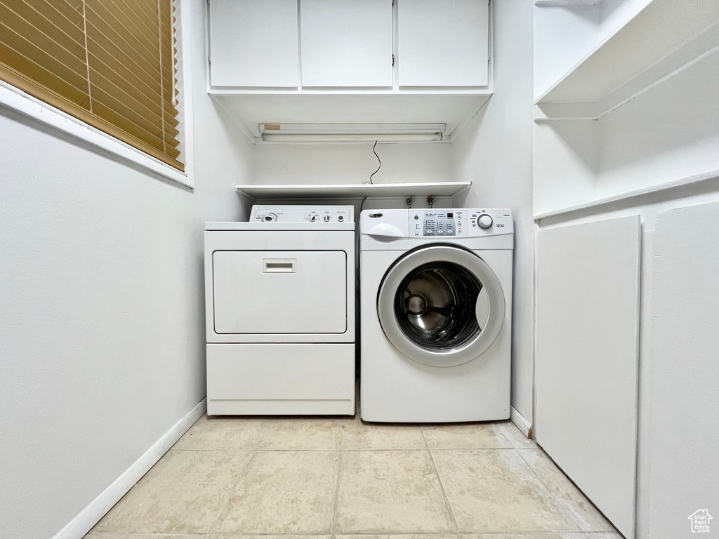 Laundry area featuring cabinets, washer and clothes dryer, and light tile floors