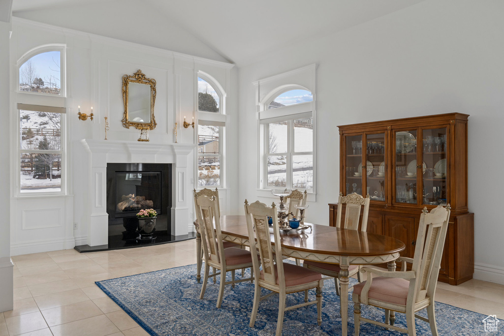 Dining room with light tile flooring, a wealth of natural light, and high vaulted ceiling