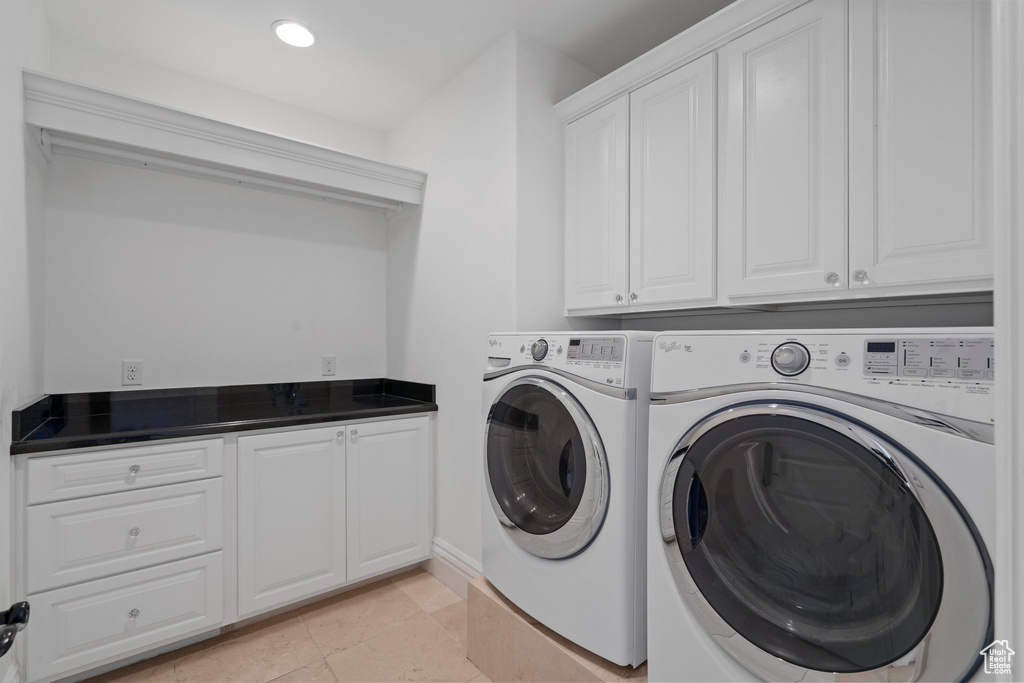 Laundry room featuring cabinets, light tile floors, and washing machine and clothes dryer