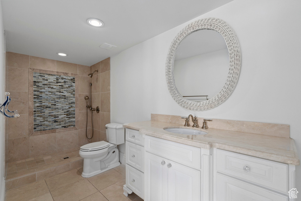 Bathroom with vanity, toilet, tile floors, and tiled shower
