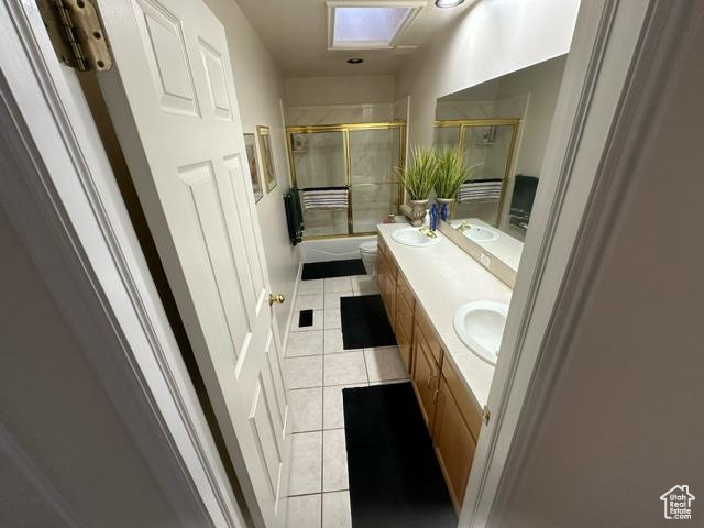 Bathroom with double sink, toilet, vanity with extensive cabinet space, and tile flooring