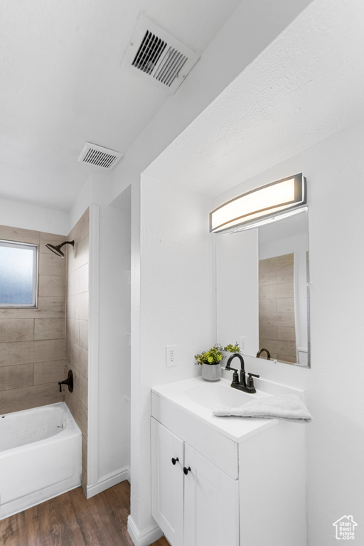 Bathroom with large vanity, hardwood / wood-style flooring, and tiled shower / bath