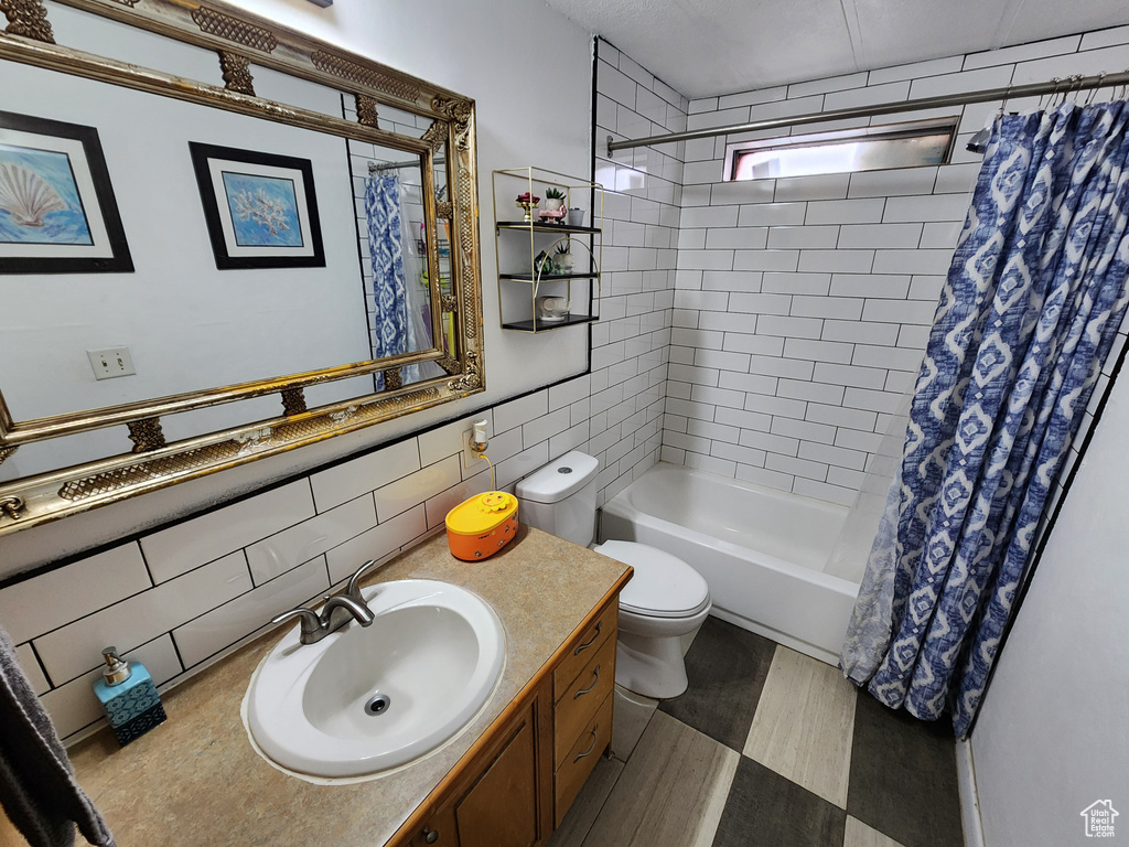 Full bathroom featuring vanity, shower / bath combo, tasteful backsplash, toilet, and tile walls