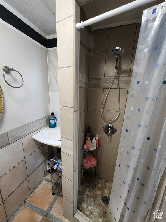 Bathroom with a shower with curtain, tile walls, tile floors, and crown molding