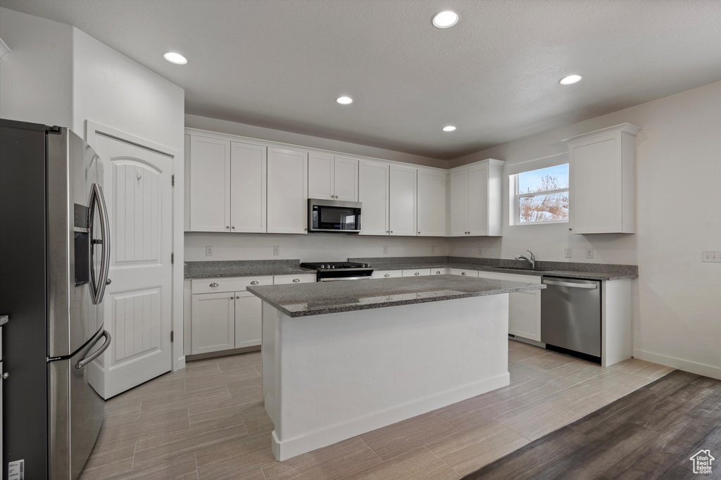 Kitchen featuring white cabinets, a center island, sink, dark stone countertops, and appliances with stainless steel finishes