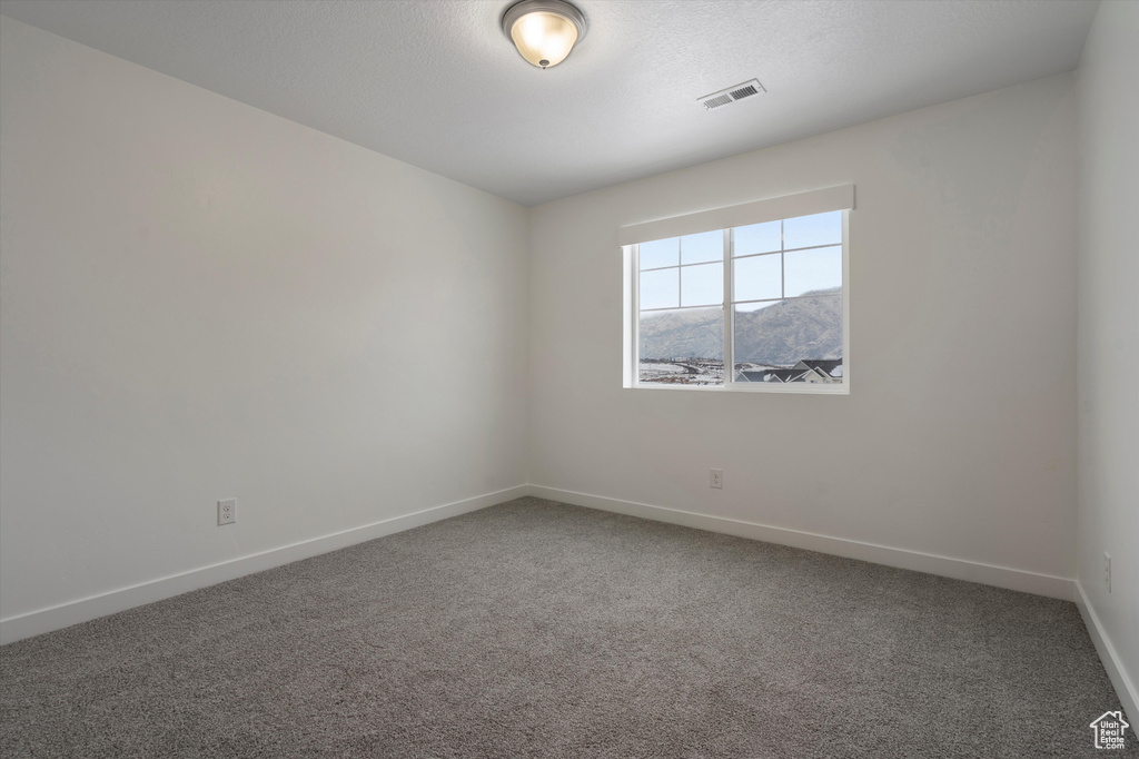 Spare room featuring dark carpet and a mountain view