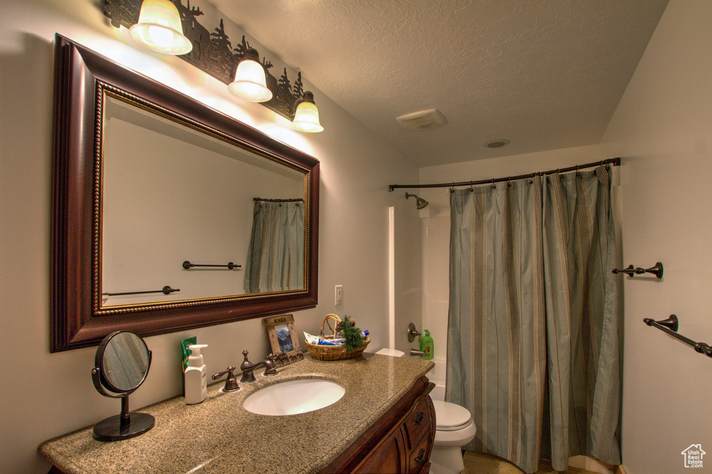 Bathroom with vanity, a textured ceiling, and toilet