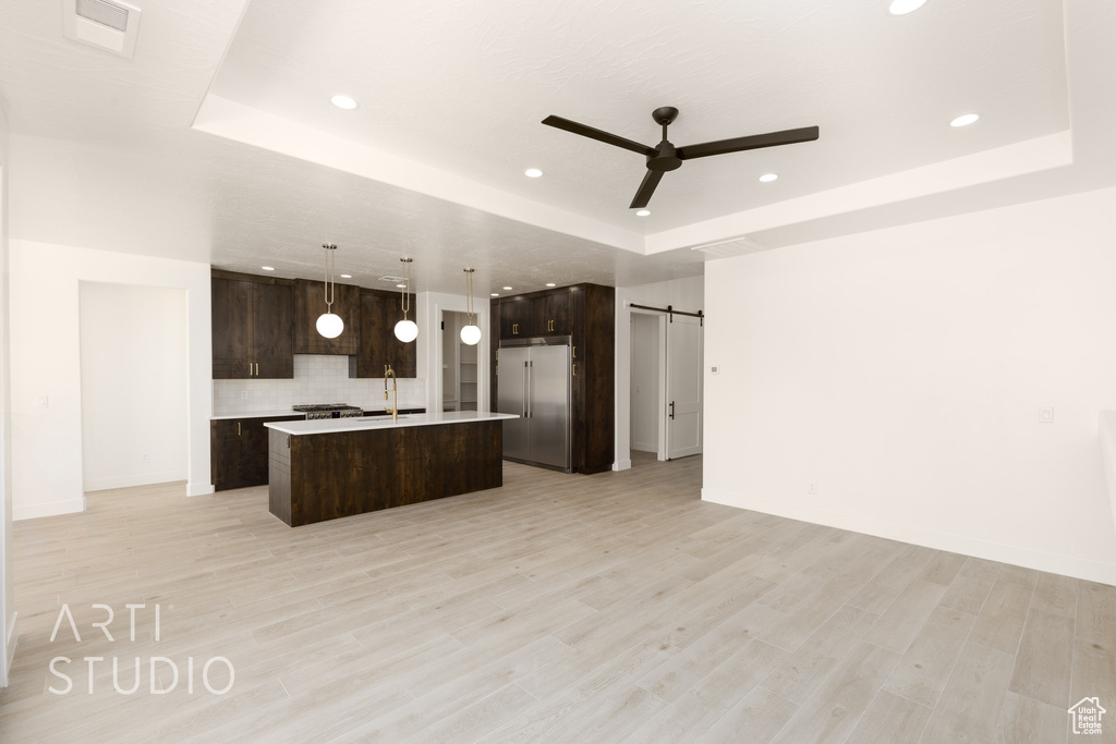 Kitchen with a barn door, a raised ceiling, a center island, and high end refrigerator