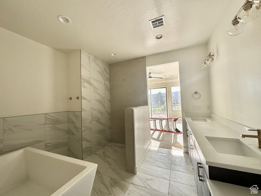 Bathroom featuring a tub, dual vanity, tile patterned floors, and ceiling fan