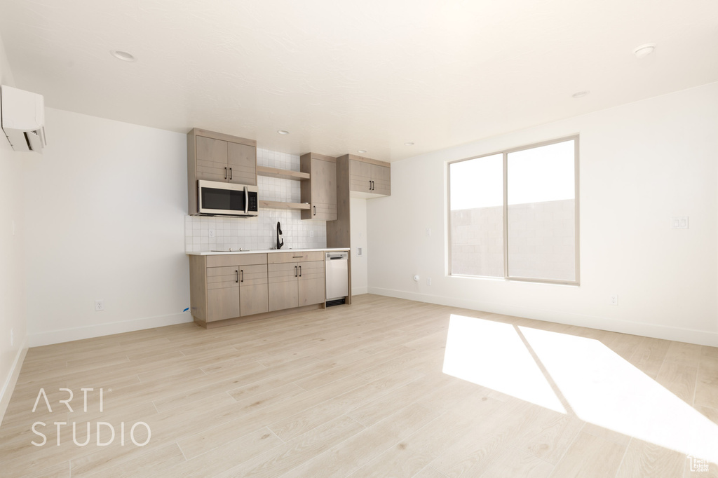 Kitchen featuring light wood-type flooring, decorative backsplash, a wall mounted air conditioner, sink, and light brown cabinetry