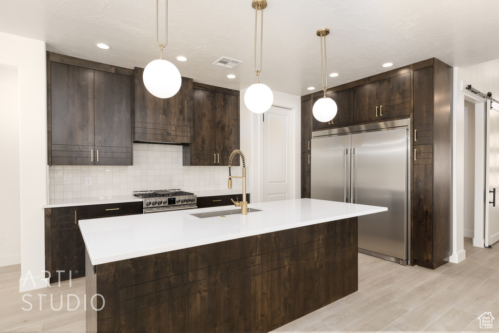 Kitchen featuring a barn door, decorative light fixtures, premium appliances, and sink