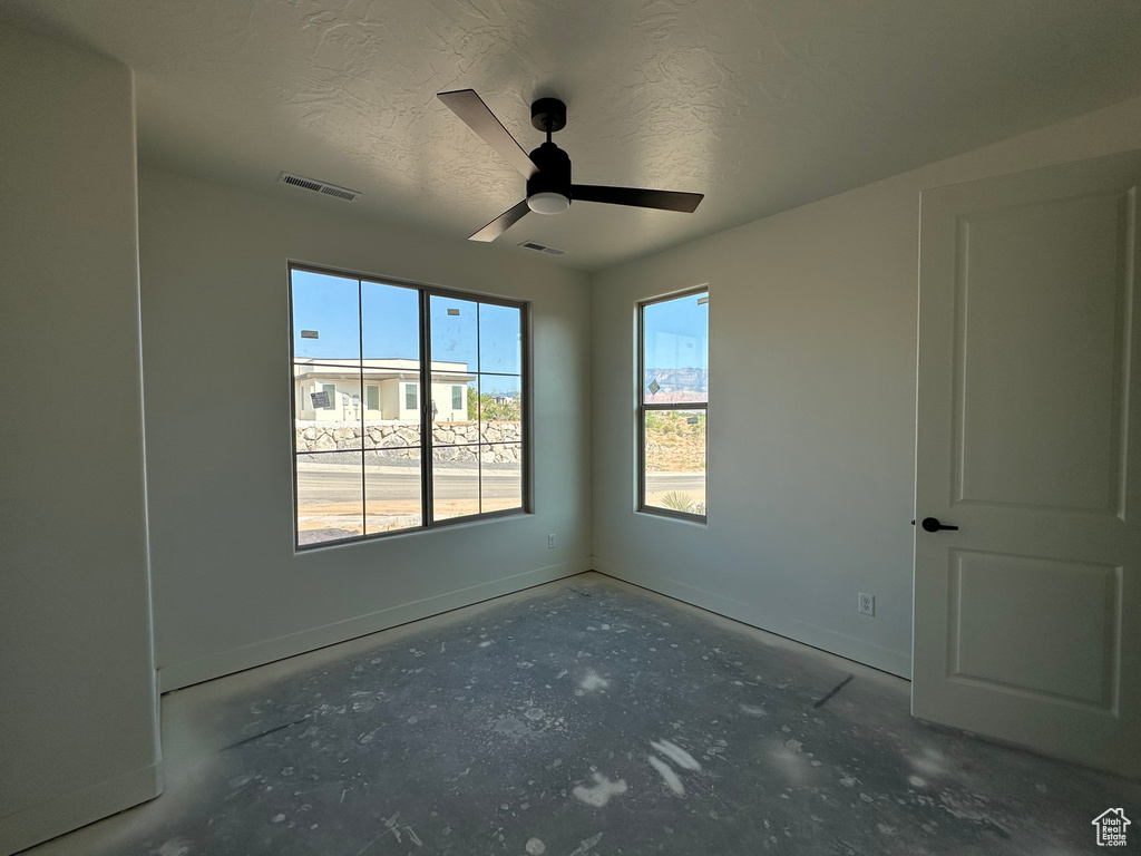 Empty room with a textured ceiling, concrete flooring, and ceiling fan