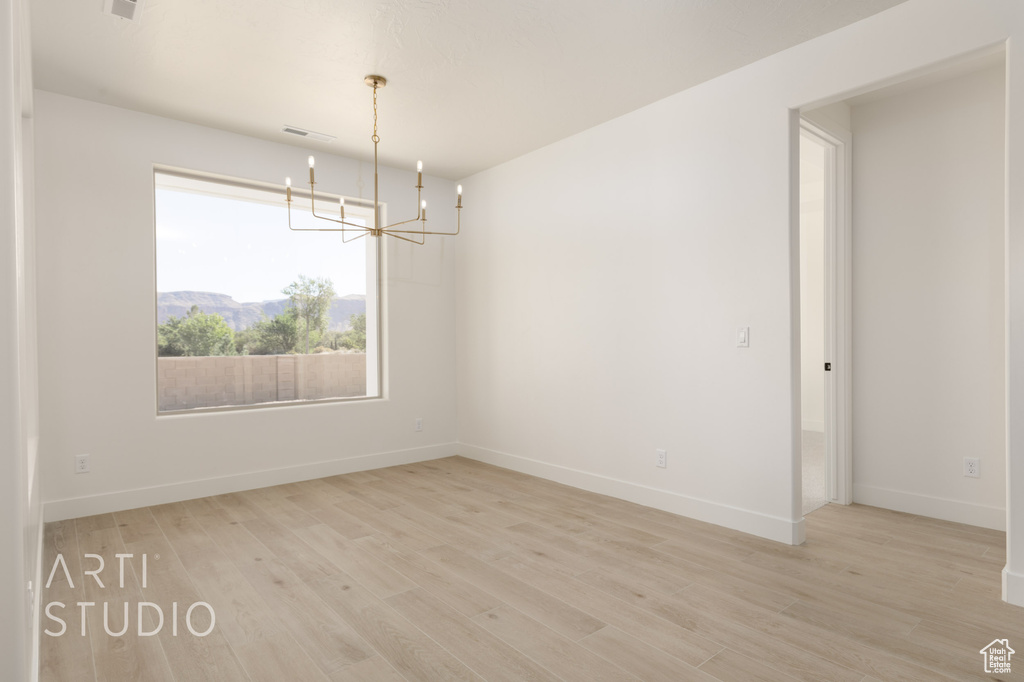 Unfurnished room featuring light hardwood / wood-style floors and a chandelier