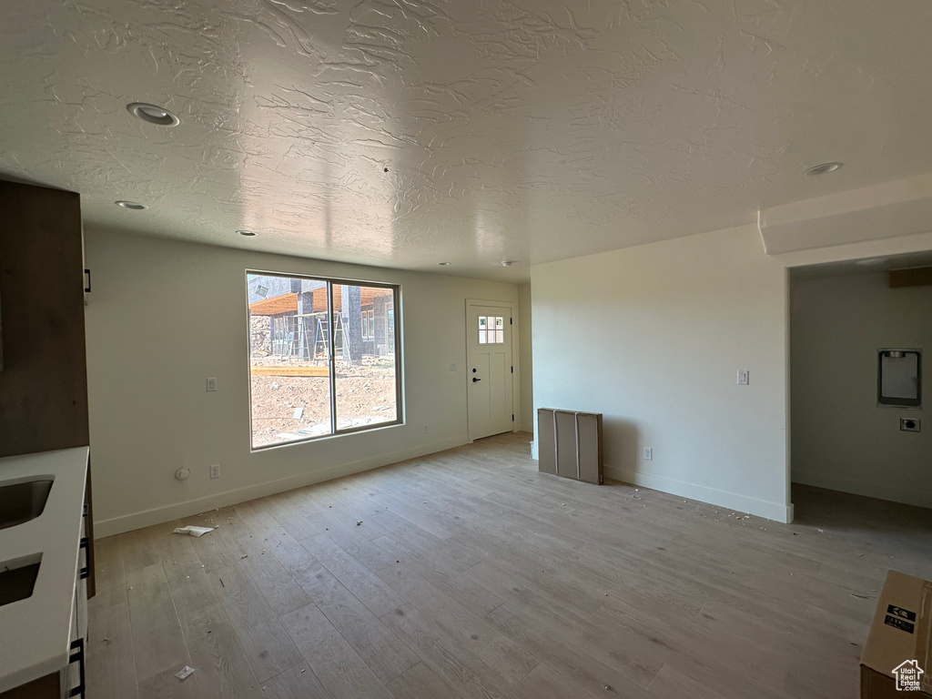 Unfurnished living room with a textured ceiling and light hardwood / wood-style flooring