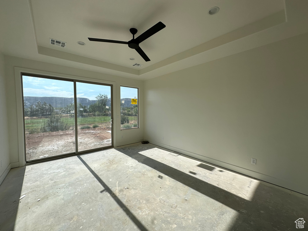 Spare room with concrete floors, ceiling fan, and a tray ceiling