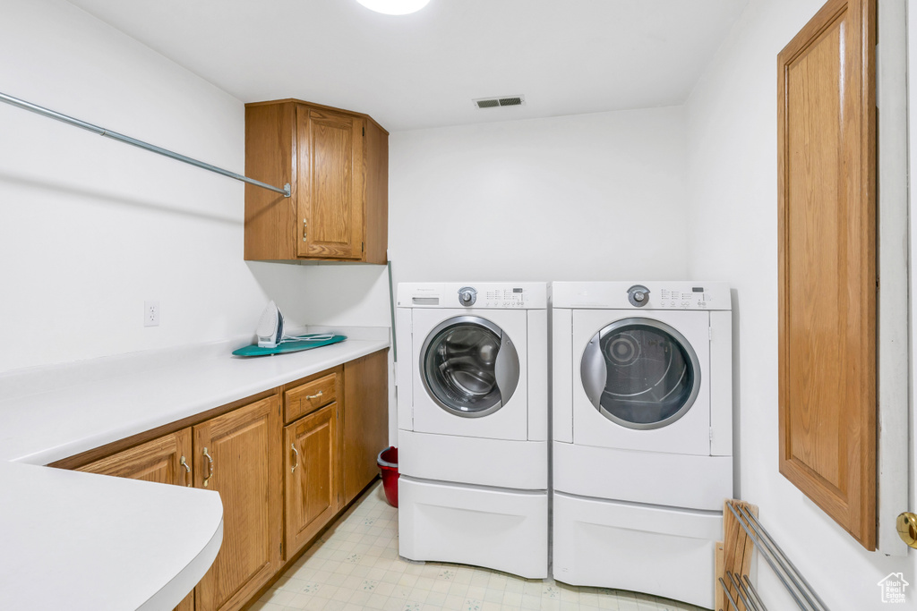 Laundry room featuring washer and clothes dryer, light tile floors, and cabinets