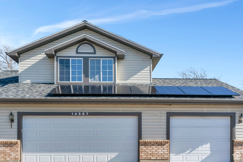 View of front facade featuring solar panels and a garage