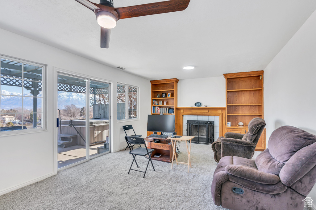Living room featuring ceiling fan, light colored carpet, and a tile fireplace