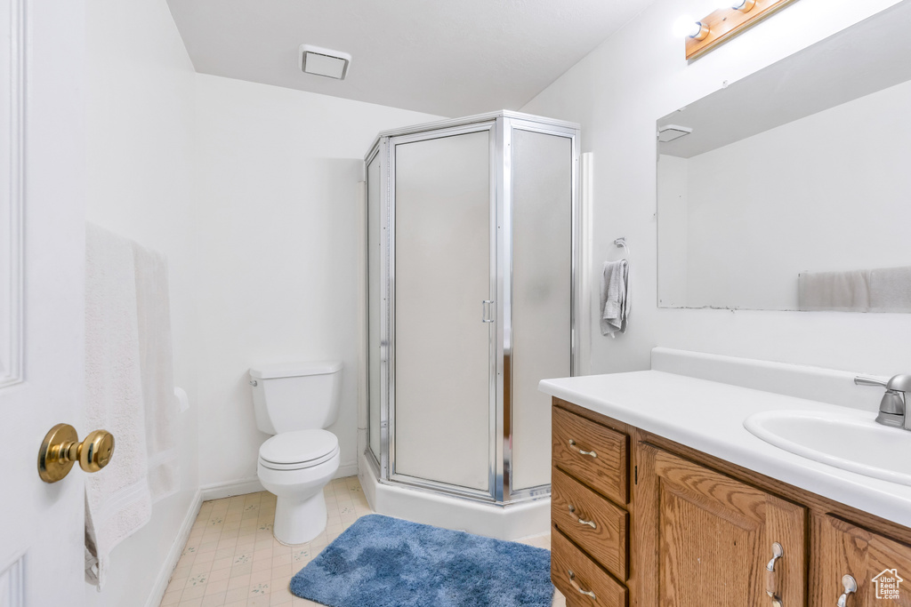 Bathroom featuring vanity, toilet, walk in shower, and tile flooring