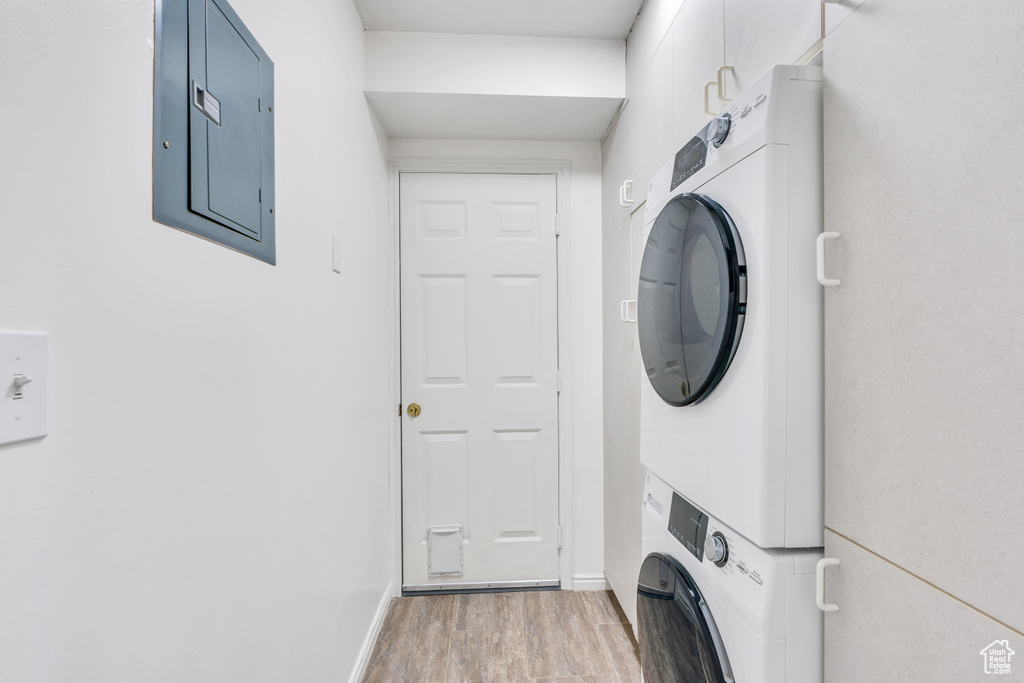 Laundry room with light hardwood / wood-style flooring and stacked washer and dryer