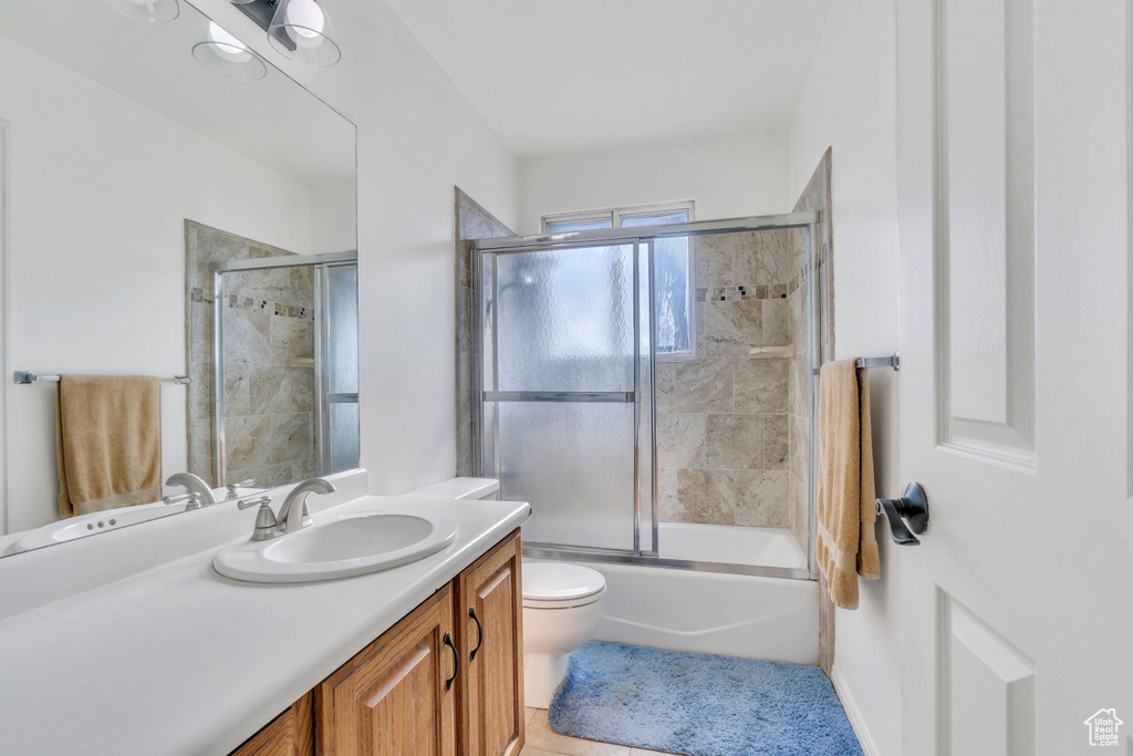 Full bathroom featuring bath / shower combo with glass door, vanity, tile flooring, and toilet