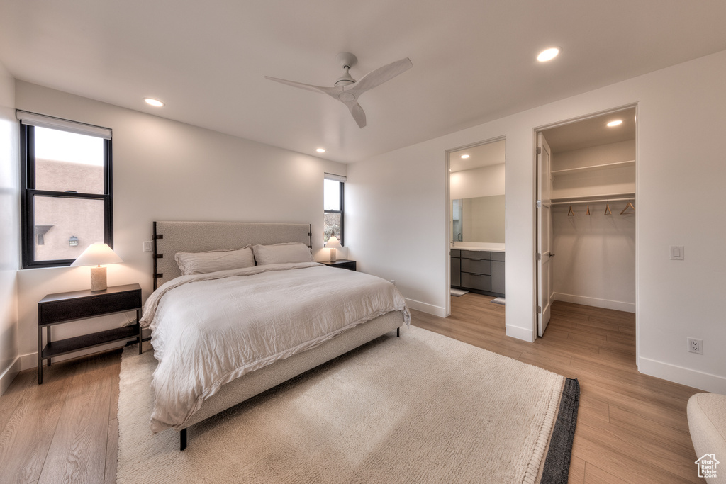Bedroom with ceiling fan, a walk in closet, connected bathroom, light hardwood / wood-style flooring, and a closet