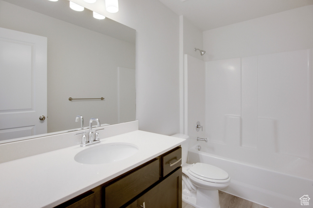 Full bathroom with toilet, hardwood / wood-style floors, vanity with extensive cabinet space, and  shower combination