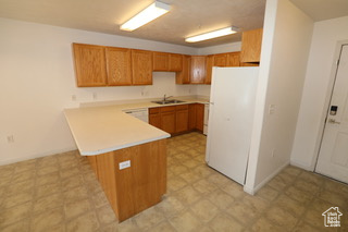 Kitchen featuring kitchen peninsula, sink, light tile floors, and white fridge
