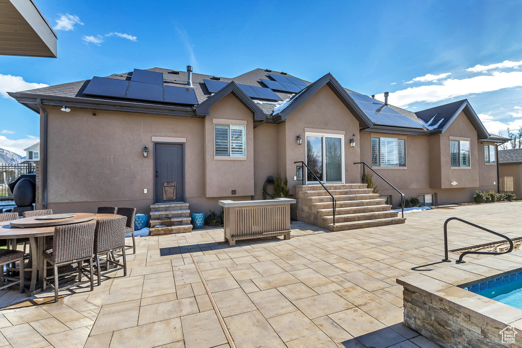 Rear view of property featuring solar panels and a patio area