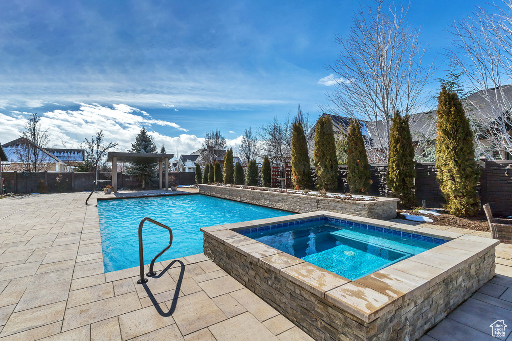 View of swimming pool featuring a patio and an in ground hot tub