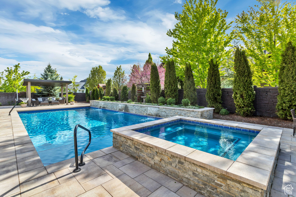 View of pool with a patio area, pool water feature, and an in ground hot tub