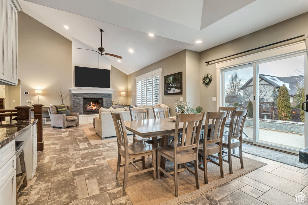 Tiled dining area featuring a healthy amount of sunlight, a fireplace, ceiling fan, and high vaulted ceiling