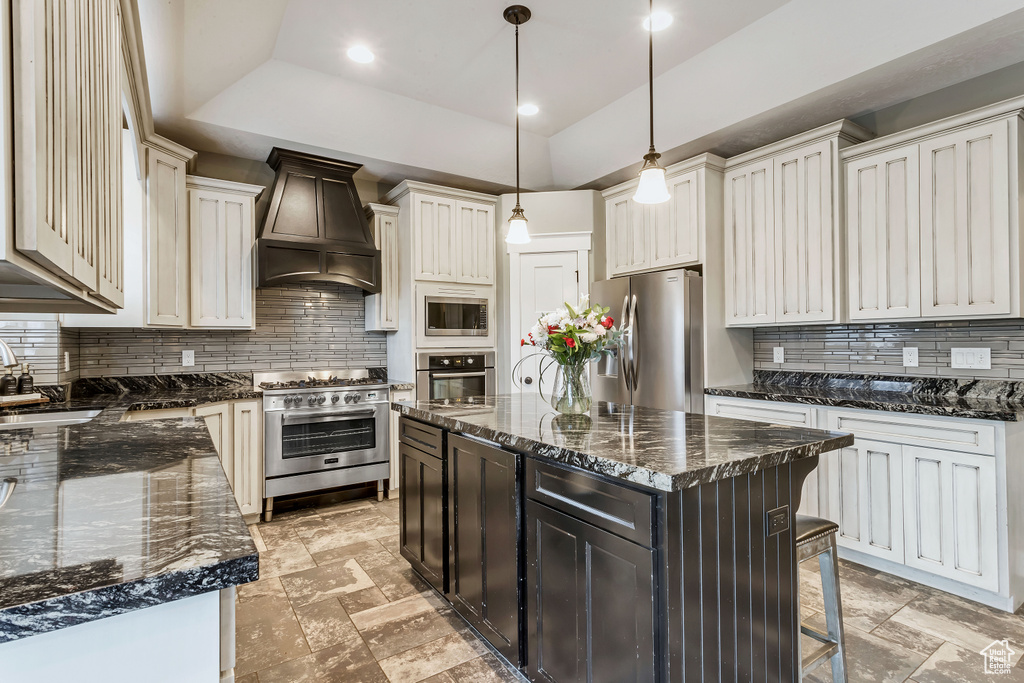 Kitchen with custom exhaust hood, stainless steel appliances, a center island, and backsplash