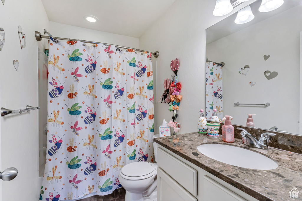 Full bathroom featuring toilet, shower / bath combo with shower curtain, and vanity with extensive cabinet space