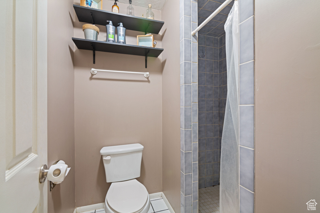 Bathroom featuring a tile shower, tile floors, and toilet