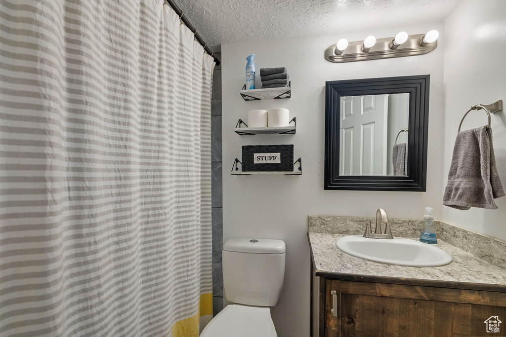 Bathroom with toilet, a textured ceiling, and vanity
