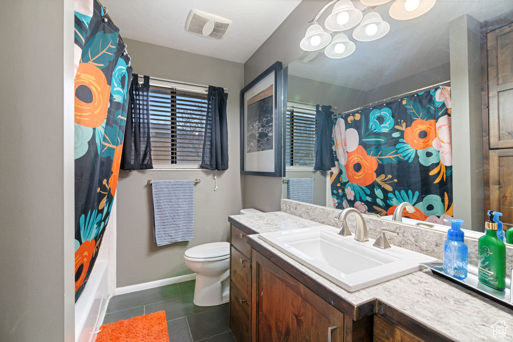 Full bathroom featuring vanity, tile floors, toilet, and shower / bathtub combination with curtain