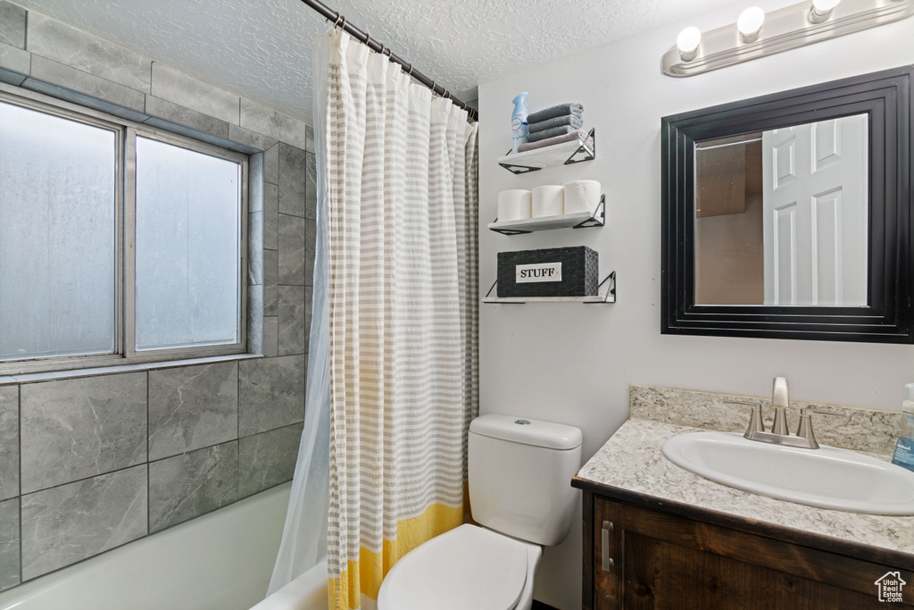 Full bathroom featuring toilet, shower / bath combo, vanity, and a wealth of natural light