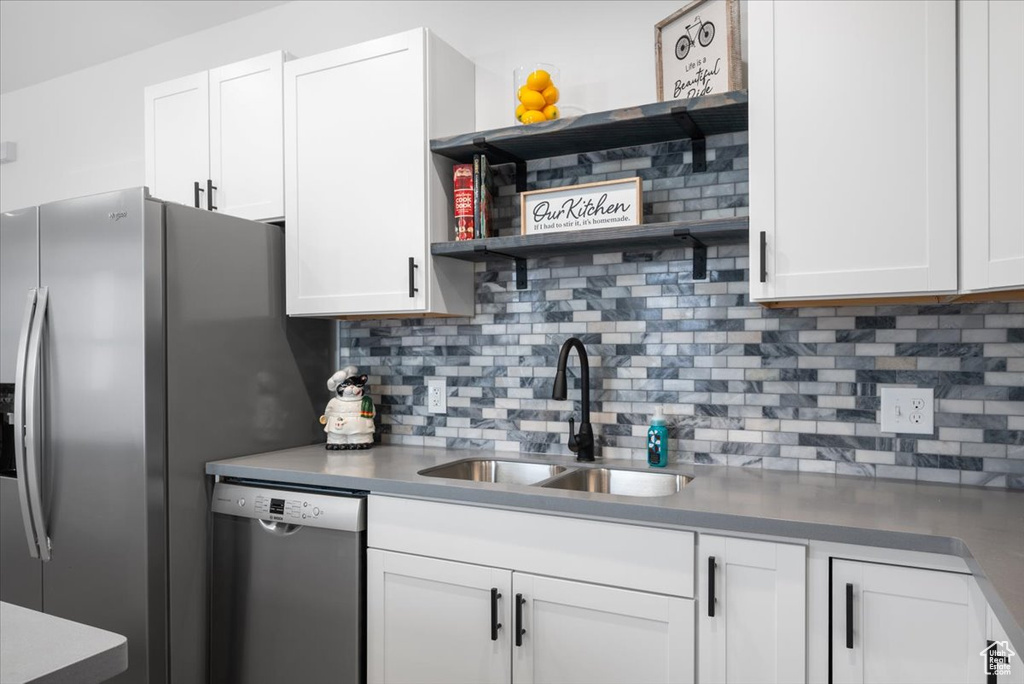 Kitchen featuring white cabinets, tasteful backsplash, stainless steel appliances, and sink