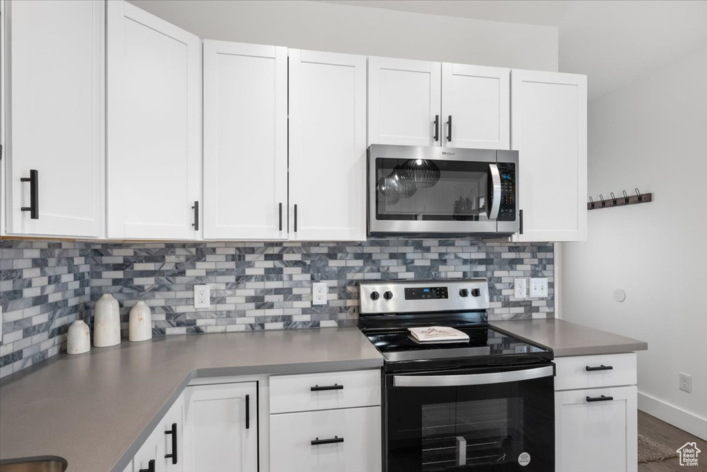 Kitchen featuring white cabinets, appliances with stainless steel finishes, and backsplash