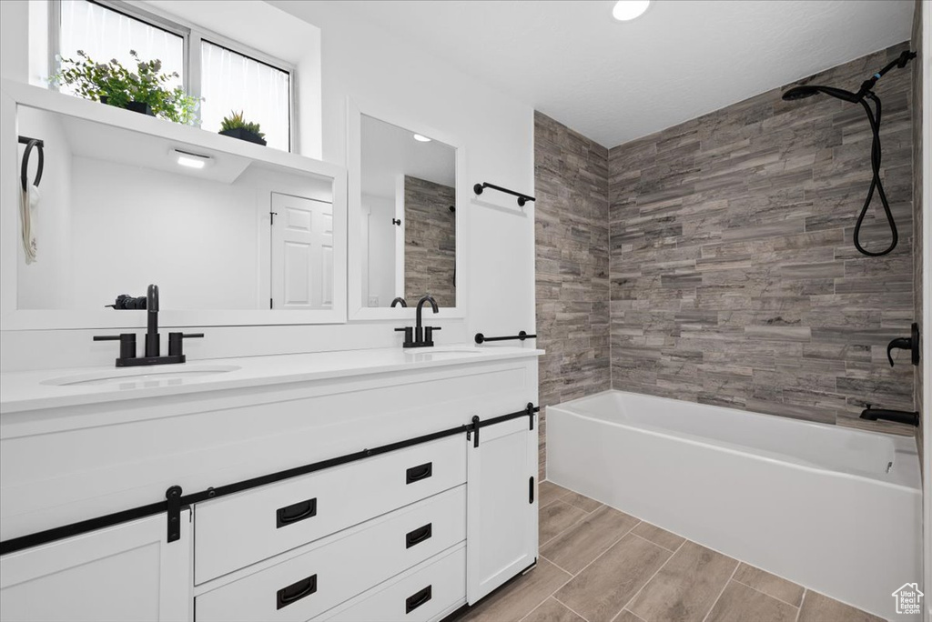 Bathroom featuring tiled shower / bath and double sink vanity