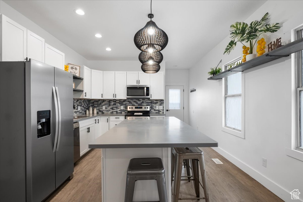 Kitchen featuring dark hardwood / wood-style floors, a kitchen island, stainless steel appliances, and a breakfast bar