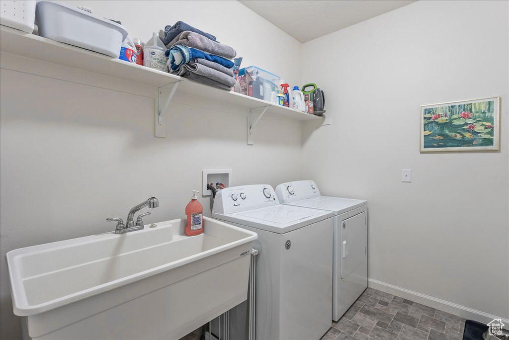 Laundry area featuring washer hookup, sink, washer and clothes dryer, and dark tile flooring