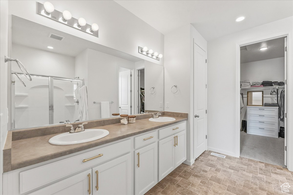 Bathroom with large vanity, dual sinks, an enclosed shower, and tile flooring