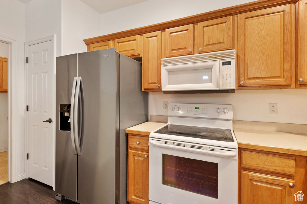 Kitchen featuring white appliances and dark wood-type flooring