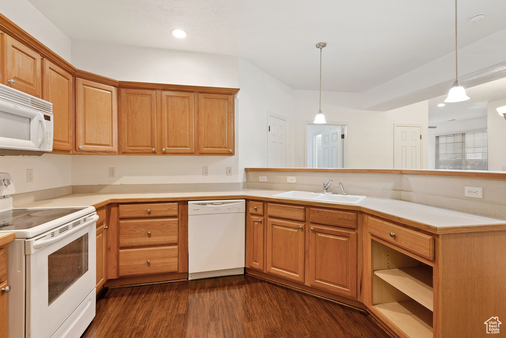 Kitchen featuring white appliances, dark hardwood / wood-style flooring, decorative light fixtures, and sink