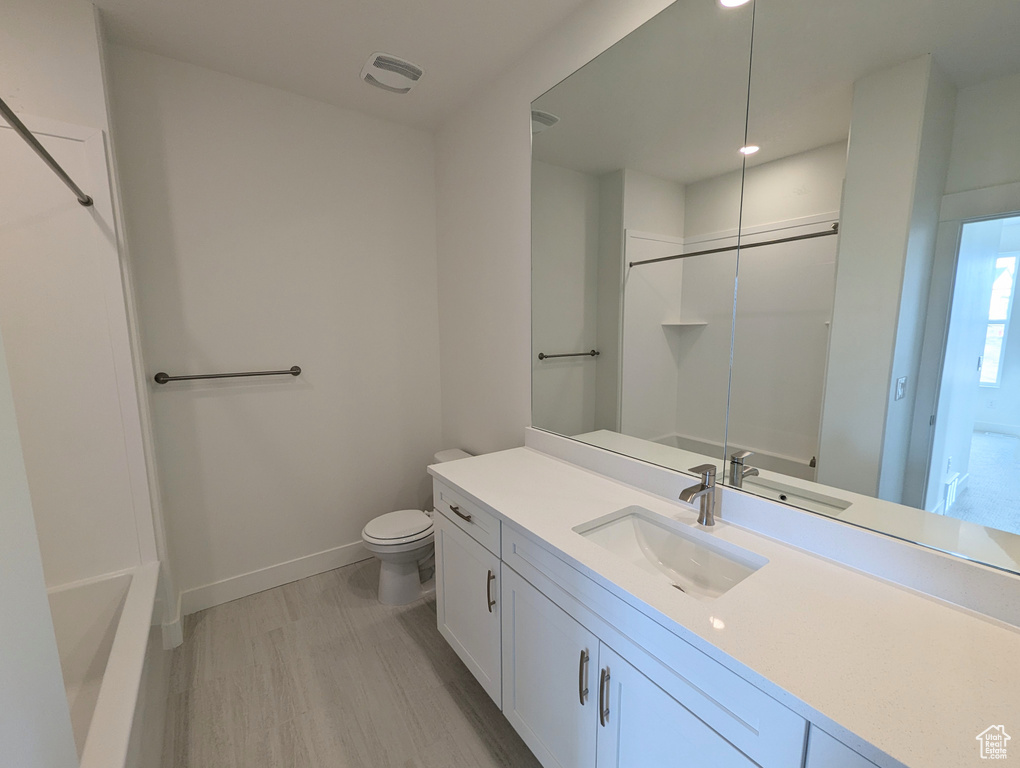Full bathroom featuring hardwood / wood-style flooring,  shower combination, vanity, and toilet