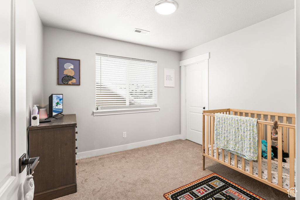 Carpeted bedroom featuring a crib