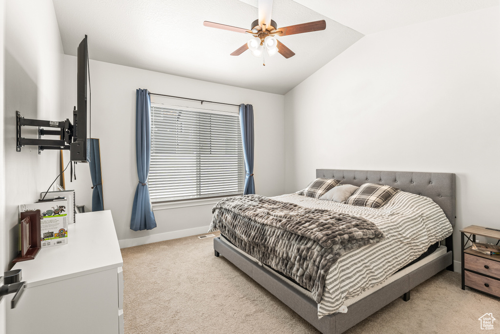 Bedroom featuring ceiling fan, light carpet, and vaulted ceiling