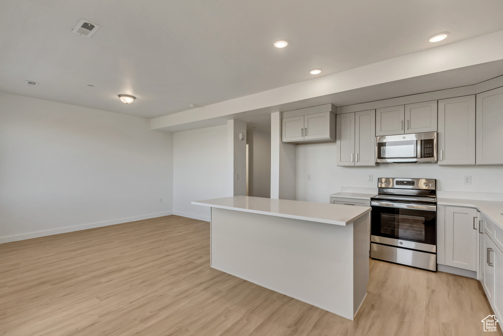 Kitchen featuring light hardwood / wood-style floors, a center island, stainless steel appliances, and white cabinetry